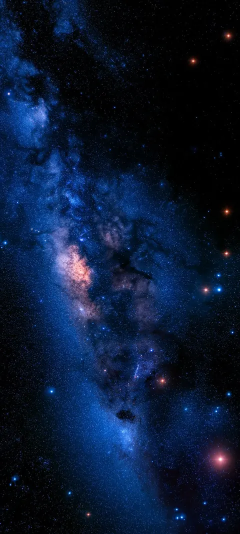 A diagonal band of the Milky Way in deep blue, with dust clouds and bright stars.