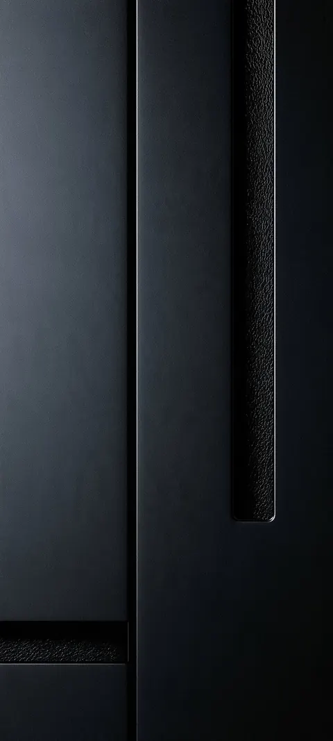 Dark matte panels meet a narrow pebbled strip, with soft edge light that keeps the upper field open for the clock.